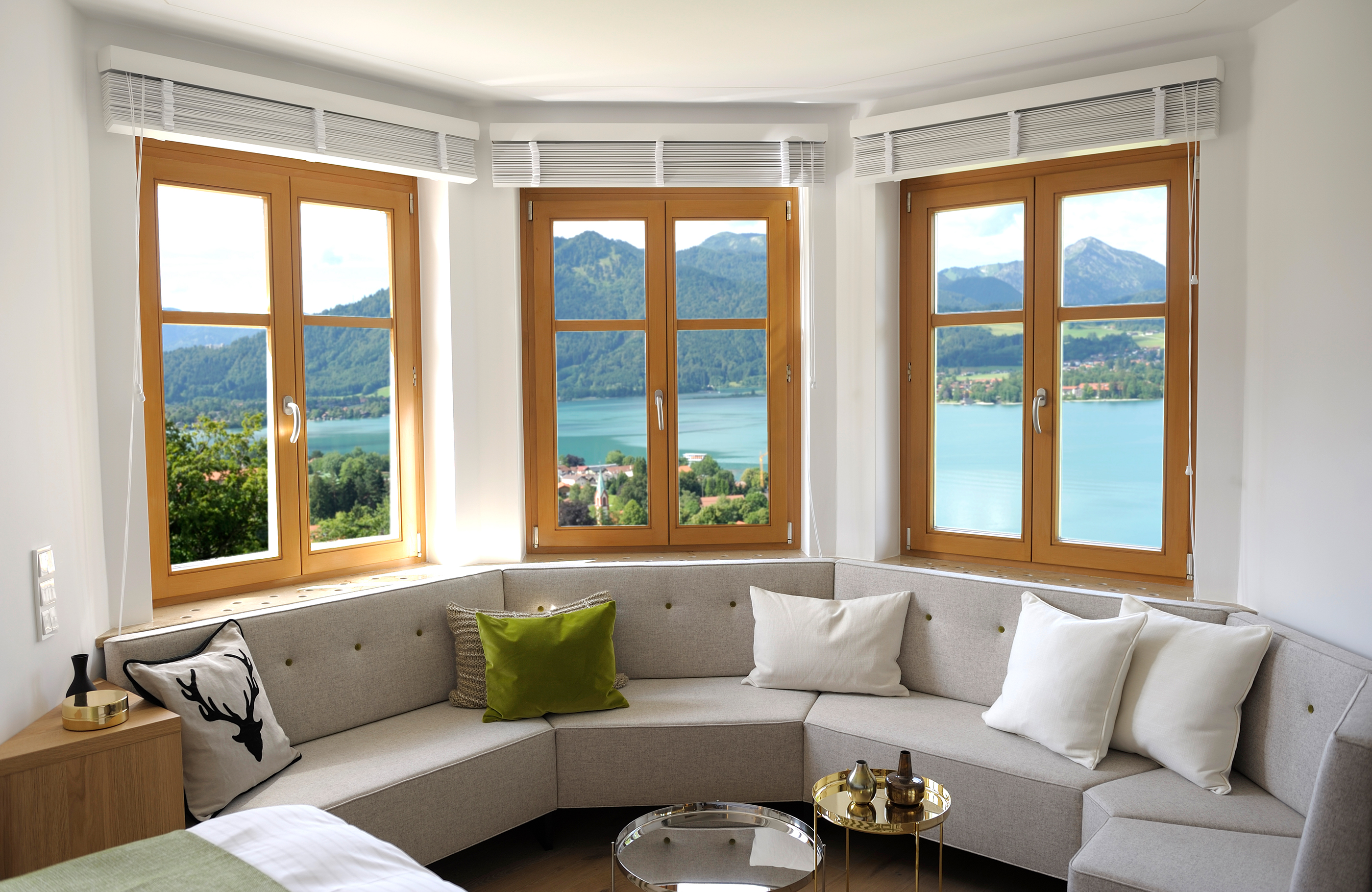 Blick über das große Sofa unter dem Fenster mit Aussicht auf den Tegernsee und die Berge