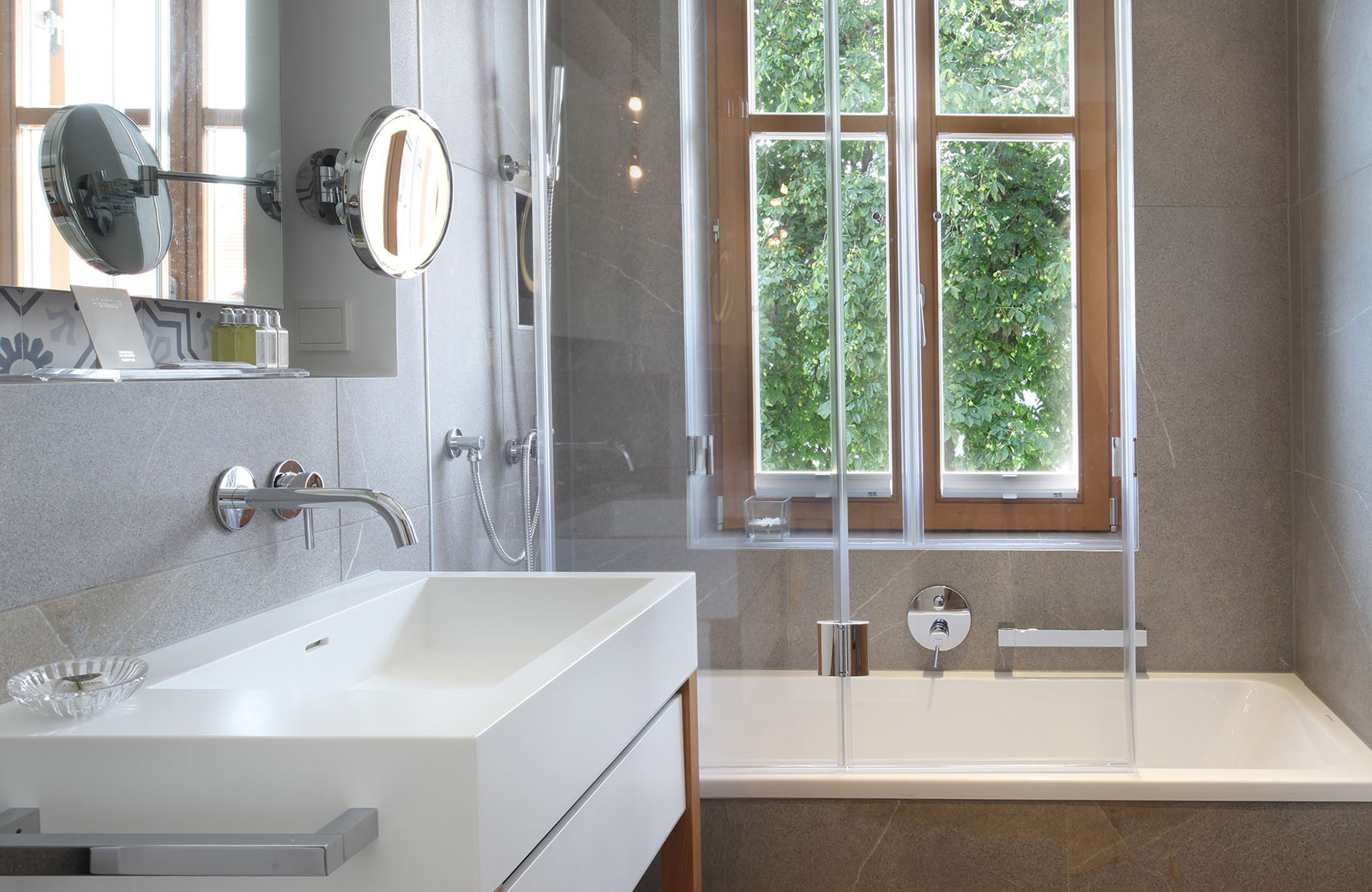 Blick in ein Badezimmer mit Duschwanne, hellem Fenster und einem großen Waschbecken