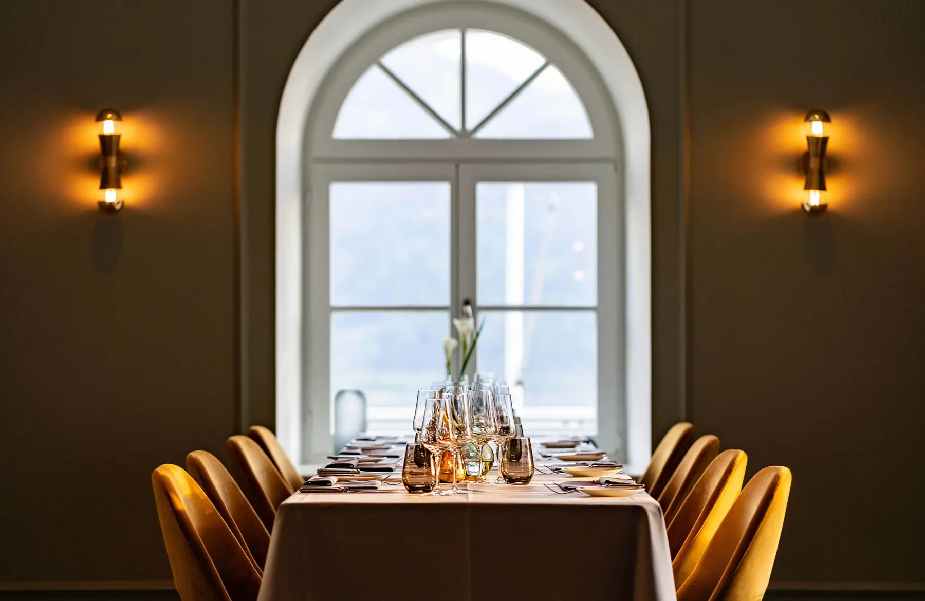 Zum Essen arrangierter Tisch und Stühle neben einem Fenster im Restaurant im Lifestyle Hotel in Bayern