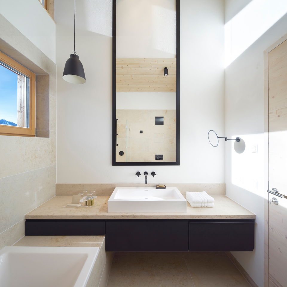 Badezimmer im Alpenchalet mit hohen Decken und hellen Fenstern