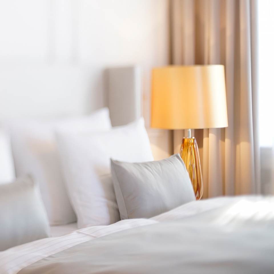 Blick auf das Kopfende eines gemütlichen Hotelbettes einer Suite im Das Tegernsee