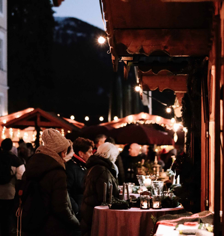 Adventsmarkt mit stehenden Personen an den Hütten