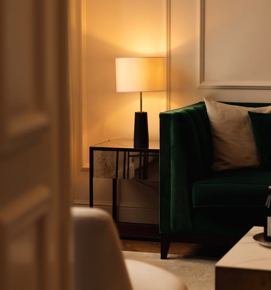 Einblick in ein Zimmer mit grüner Couch und stimmungsvoller Beleuchtung