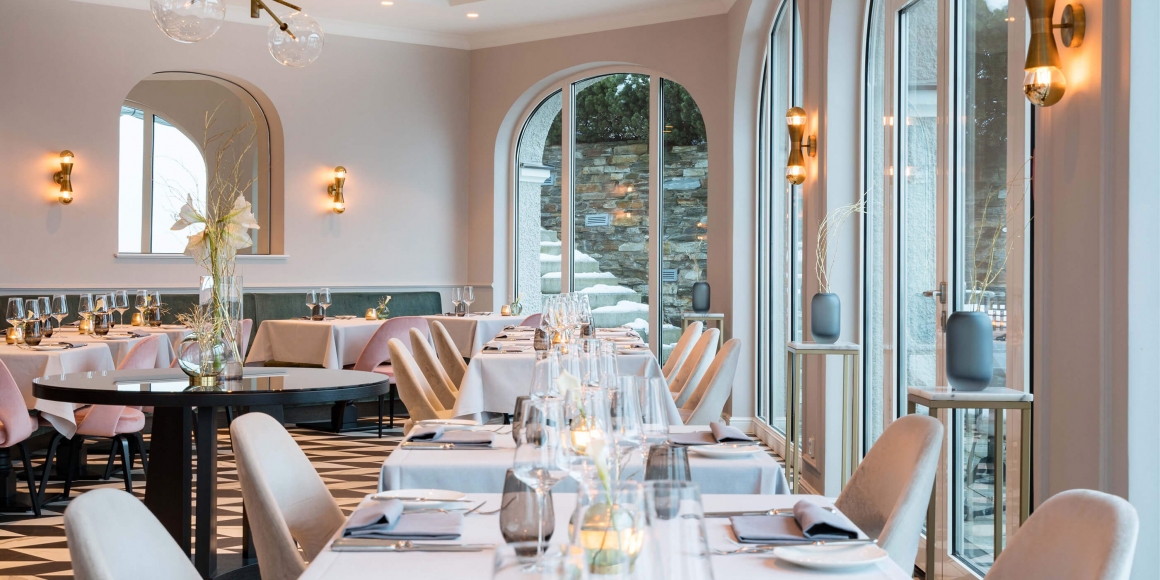 Aufnahme des Innenraums im Restaurant Senger am Tegernsee mit mehreren in grau-weißen Farben eingedeckten Tischen.