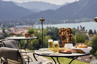 Biergarten mit gedecktem Tisch, Stühle und Blick auf den Tegernsee
