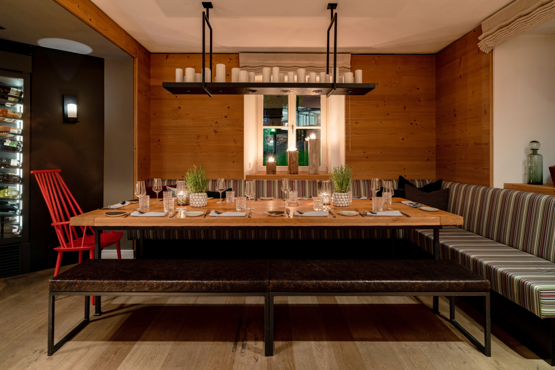 Weinstube mit großer Tafel, Sitzbänken und Fenster im Hintergrund.